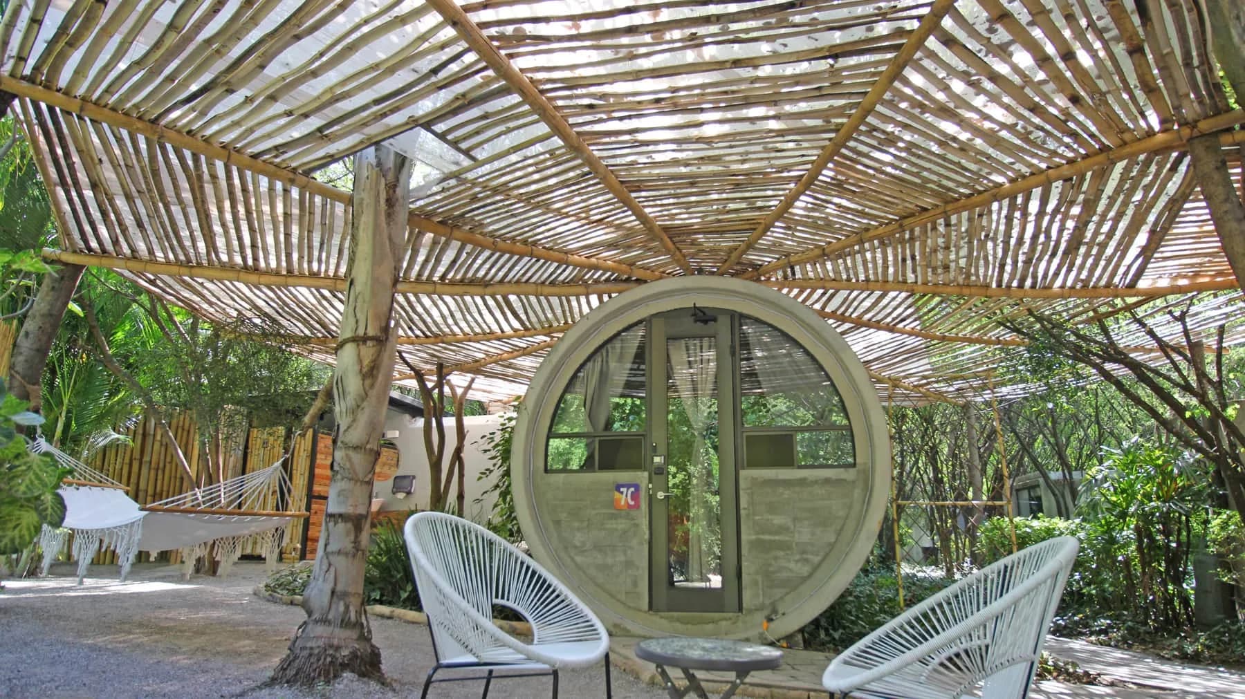 Habitación cilíndrica de Kubhotel integrada entre los árboles, junto a un estanque